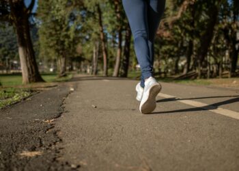 person in blue denim jeans and white sneakers walking on road