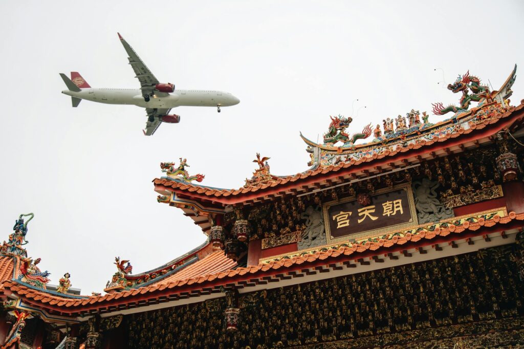 passenger airplane flying over a traditional chinese building