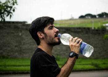 man wearing black shirt drinking water