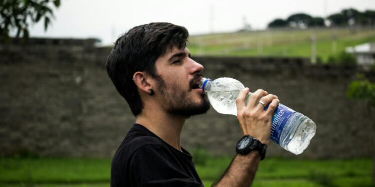 man wearing black shirt drinking water