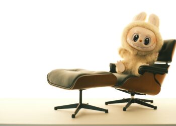 A cute stuffed animal sits on a comfortable chair.
