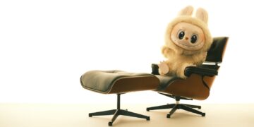 A cute stuffed animal sits on a comfortable chair.