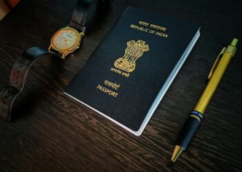 a passport, watch and pen on a table