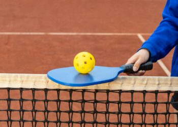 a person holding a tennis racket and a ball on a tennis court