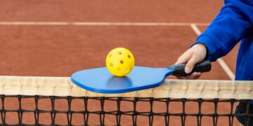 a person holding a tennis racket and a ball on a tennis court