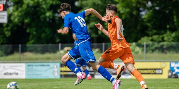 man in blue and orange jersey shirt running on green grass field during daytime